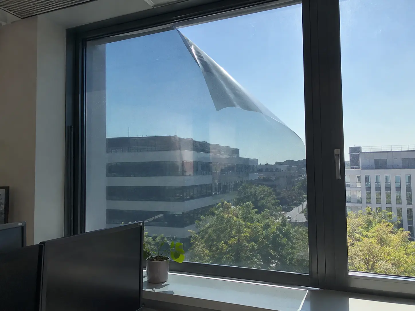 Sonnenschutzfolie löst sich an der Ecke einer Bürofensterscheibe ab