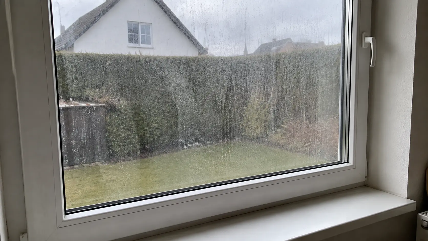 Stark verschmutztes Wohnzimmerfenster mit Kalkflecken und festgesetztem Schmutz